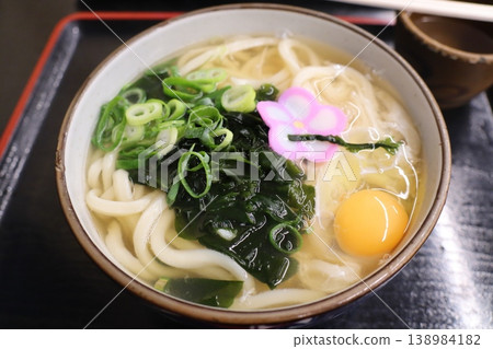 A warm bowl of udon noodles garnished with egg yolk and fish cake. A warm bowl of udon noodles garnished with egg yolk and fish cake. 138984182