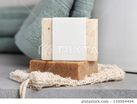 Handmade solid soap bars with blank label mockup on soap saver bag near sage green towel 138984494