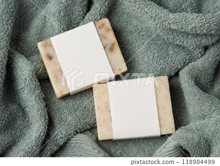 Beige solid soap bars with blank paper label mockup on light green bath towel, unbranded packaging 138984499