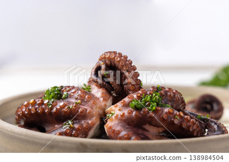 Boiled octopus on ceramic plate with olive oil and parsley dressing. Mediterranean cold appetizer Boiled octopus on ceramic plate with olive oil and parsley dressing. Mediterranean cold appetizer 138984504