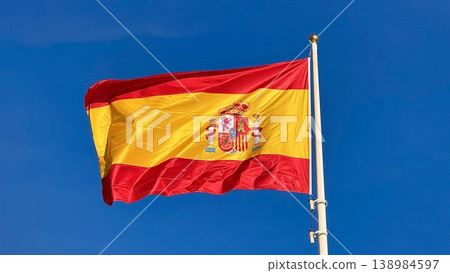 Spanish Flag Waving on Flagpole Against Clear Blue Sky, National Symbol of Spain Spanish Flag Waving on Flagpole Against Clear Blue Sky, National Symbol of Spain 138984597