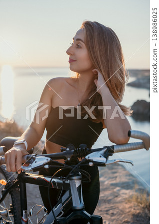 Woman bicycle sunset posing with a mountain bike on a coastal cliff during golden hour for fitness and travel inspiration Woman bicycle sunset posing with a mountain bike on a coastal cliff during golden hour for fitness and travel inspiration 138986025