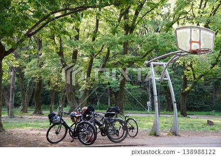 A basketball hoop and parked bicycles in a park surrounded by fresh greenery (a scene of sports and relaxation). A basketball hoop and parked bicycles in a park surrounded by fresh greenery (a scene of sports and relaxation). 138988122