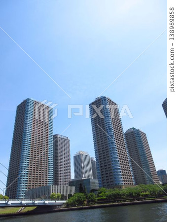 The cluster of tower apartments in Tsukuda River City 21 along the Sumida River and the blue sky. The cluster of tower apartments in Tsukuda River City 21 along the Sumida River and the blue sky. 138989858