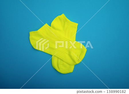 Neatly folded yellow socks on a blue background. A stylish sports accessory. Flat lay Neatly folded yellow socks on a blue background. A stylish sports accessory. Flat lay 138990182