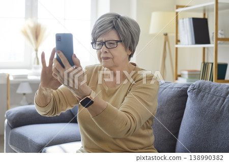 Senior woman with presbyopia and vision problem using smartphone at home 138990382