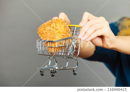 Woman hand holding shopping cart with bread 138990425