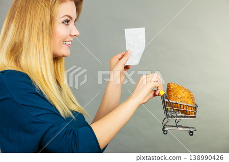 Happy woman holding shopping basket with bread Happy woman holding shopping basket with bread 138990426