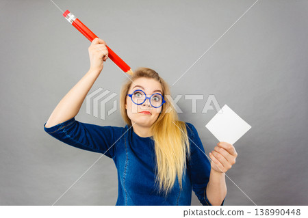 Confused woman holds big pencil note paper in hand 138990448