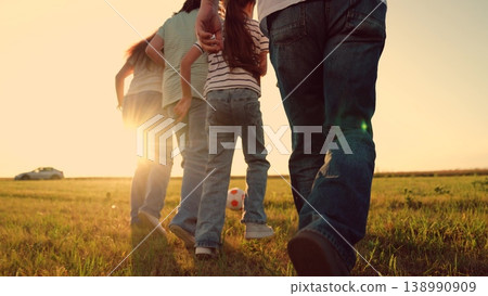 Parents run with child kid playing football green lawn, children kicking ball, mother father girl boy happy family sunset, community health concept: active family playing football outdoors at sunset 138990909