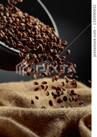 Freshly roasted coffee beans are poured into a bag. Freshly roasted coffee beans are poured into a bag. 138990932