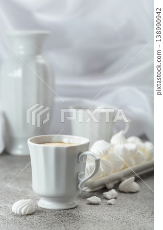 Black coffee in white porcelain cup and white small French meringues. Black coffee in white porcelain cup and white small French meringues. 138990942