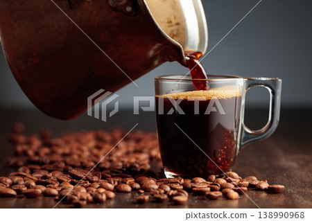 Black coffee is poured into a glass cup. 138990968