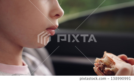 little girl child eating burger in car, happy person, Joyful kid traveler, eating while buckled up, burger time in car, roadside hunger, fresh air and food, travel companion, young one s delight little girl child eating burger in car, happy person, Joyful kid traveler, eating while buckled up, burger time in car, roadside hunger, fresh air and food, travel companion, young one s delight 138990991