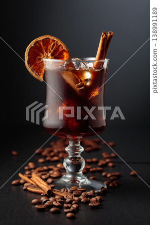 Iced coffee garnished with a cinnamon stick and a dried orange slice. 138991189
