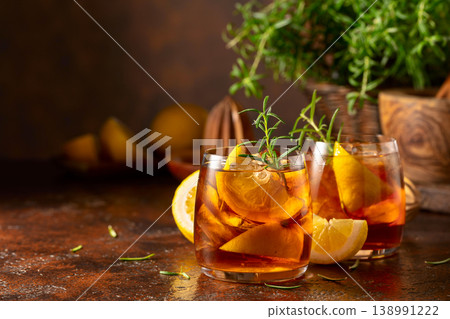 Iced tea or cocktail with ice, rosemary and lemon slices on the old brown table. Iced tea or cocktail with ice, rosemary and lemon slices on the old brown table. 138991222