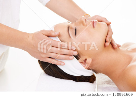 Spa, hands and face massage with a woman customer in studio isolated on a white background for stress relief. Head, luxury treatment and a young person at the salon for health, wellness or to relax Spa, hands and face massage with a woman customer in studio isolated on a white background for stress relief. Head, luxury treatment and a young person at the salon for health, wellness or to relax 138991609