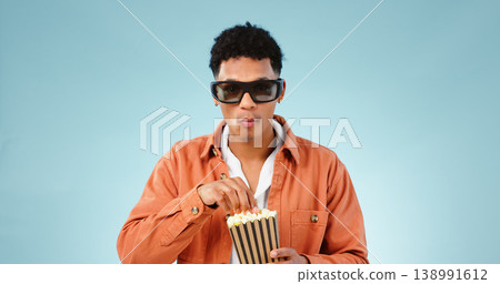 Man popcorn and studio with glasses for 3d movie with eating snack, streaming video and cinema by blue background. Person, sunglasses and corn fast food to watch show, cartoon and film in theater Man popcorn and studio with glasses for 3d movie with eating snack, streaming video and cinema by blue background. Person, sunglasses and corn fast food to watch show, cartoon and film in theater 138991612