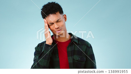 Tired, studio or man with headache, burnout or fatigue in crisis with head pain or emergency. Depression problem, face or person frustrated by ptsd, migraine or stress isolated on blue background Tired, studio or man with headache, burnout or fatigue in crisis with head pain or emergency. Depression problem, face or person frustrated by ptsd, migraine or stress isolated on blue background 138991955