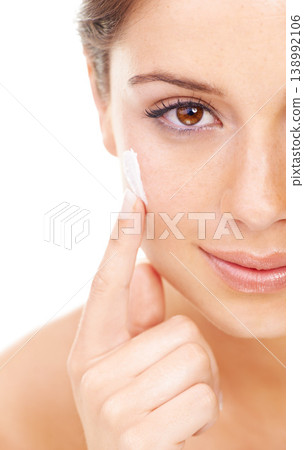 Portrait, beauty and lotion with a woman in studio isolated on a white background for natural wellness. Face, skincare and luxury cream with a confident young model looking to apply a product 138992106