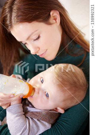 Face, woman and holding of baby with bottle for feeding in home for health, diet and nutrition with formula for hunger. Mother, watch and son for growth, development or milestone for future with care Face, woman and holding of baby with bottle for feeding in home for health, diet and nutrition with formula for hunger. Mother, watch and son for growth, development or milestone for future with care 138992321