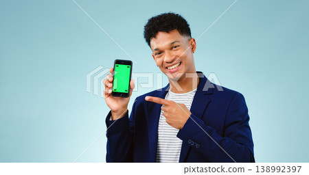 Happy man, pointing and phone for green screen on blue background in studio, portrait and mockup in New York. Male model, entrepreneur or creative with mobile of offer, promotion or discount on web Happy man, pointing and phone for green screen on blue background in studio, portrait and mockup in New York. Male model, entrepreneur or creative with mobile of offer, promotion or discount on web 138992397