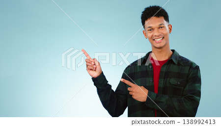 Portrait, smile and man with hand pointing to studio for mockup, space or news on blue background. Presentation, smile and face of model show information, announcement or menu, guide or how to steps Portrait, smile and man with hand pointing to studio for mockup, space or news on blue background. Presentation, smile and face of model show information, announcement or menu, guide or how to steps 138992413