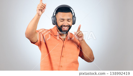 Happy man, headphones and dancing or listening to music for audio streaming against studio grey background. Male person enjoying sound track, podcast or radio with headset for rhythm on mockup space Happy man, headphones and dancing or listening to music for audio streaming against studio grey background. Male person enjoying sound track, podcast or radio with headset for rhythm on mockup space 138992419