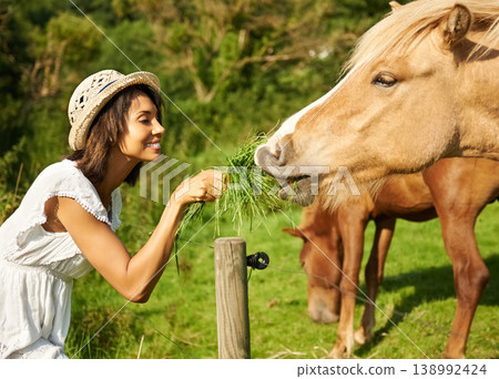 Woman, horse and outdoor for feeding grass with smile, care or love for pet at farm, countryside or spring. Girl, equine animal and happy with food for health, nutrition and diet in meadow for summer 138992424