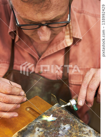 Man, jewelry and hands or torch tools for creative art manufacturing, metal process in workshop. Mature person, expert and equipment or silver heating as handmade business, flame craft or iron design Man, jewelry and hands or torch tools for creative art manufacturing, metal process in workshop. Mature person, expert and equipment or silver heating as handmade business, flame craft or iron design 138992429