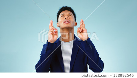 Man, fingers crossed or good luck in studio for prize, promotion or competition giveaway by blue background. Model, hope and emoji for wish for blessing, nervous and waiting for results in mockup 138992546