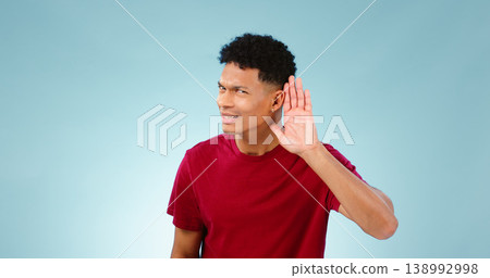 Portrait, overhearing and hand gesture for eavesdropping with a man listening in studio on a blue background. Emoji, communication and secret with a confused young person in doubt about news Portrait, overhearing and hand gesture for eavesdropping with a man listening in studio on a blue background. Emoji, communication and secret with a confused young person in doubt about news 138992998