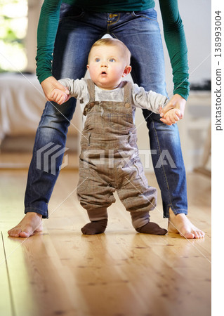 Mother, baby and helping with walking in home with support, trust and care for childhood development. Toddler, little boy and holding hand for motor skills, assistance and mobility in living room Mother, baby and helping with walking in home with support, trust and care for childhood development. Toddler, little boy and holding hand for motor skills, assistance and mobility in living room 138993004