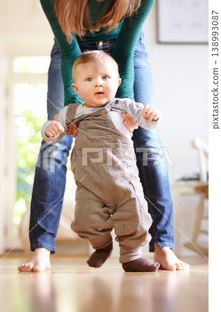 Mother, baby and face with help for walking in home for motor skills, development or milestone with assistance. Son, toddler and excited for mobility, movement or freedom in living room with support Mother, baby and face with help for walking in home for motor skills, development or milestone with assistance. Son, toddler and excited for mobility, movement or freedom in living room with support 138993087