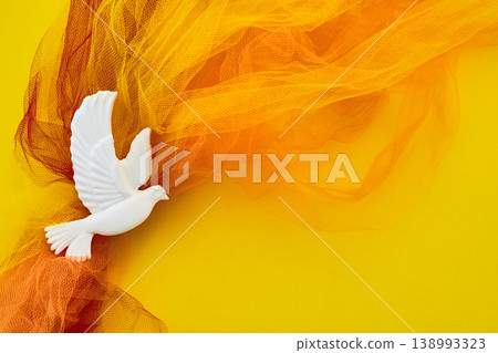Pentecost. White dove flying over orange tulle representing peace Pentecost. White dove flying over orange tulle representing peace 138993323