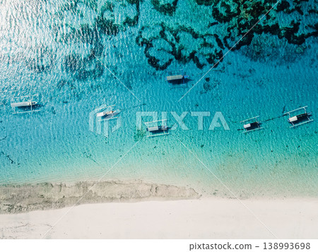 Drone view of turquoise ocean with traditional boats near white sandy beach in Bali Drone view of turquoise ocean with traditional boats near white sandy beach in Bali 138993698