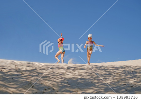 Funny girls in leopard print swimsuits have fun running and dancing on the sand by the sea Funny girls in leopard print swimsuits have fun running and dancing on the sand by the sea 138993716