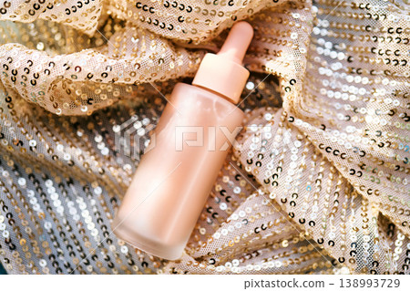 Cosmetic serum bottle on shimmering sequin fabric Cosmetic serum bottle on shimmering sequin fabric 138993729