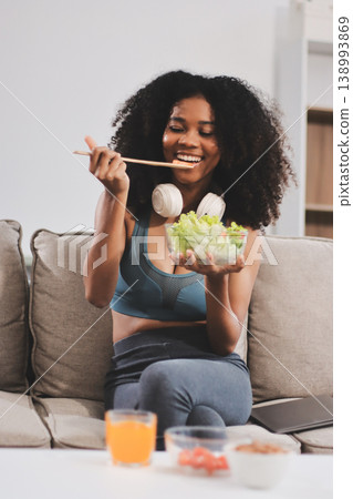 Young nutritionist showing bell peppers during an online video call consulting about healthy eating, sitting at home at a table with vegetables, laptop and measuring tape Young nutritionist showing bell peppers during an online video call consulting about healthy eating, sitting at home at a table with vegetables, laptop and measuring tape 138993869