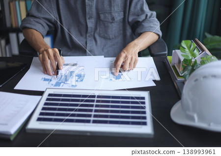 Professional Engineer Planning Sustainable Solar Energy Installation with Blueprints in office. Professional Engineer Planning Sustainable Solar Energy Installation with Blueprints in office. 138993961
