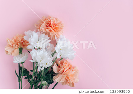 Beautiful peach pastel carnation and white chrysanthemum flowers on a pink background. Beautiful peach pastel carnation and white chrysanthemum flowers on a pink background. 138993990