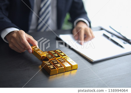 Gold investment Concept. Businessman working on financial planning and gold investment analysis with bullion on desk. 138994064