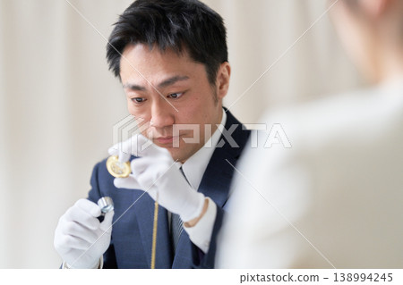 A male appraiser wearing white gloves is using a magnifying glass to examine an object. A male appraiser wearing white gloves is using a magnifying glass to examine an object. 138994245