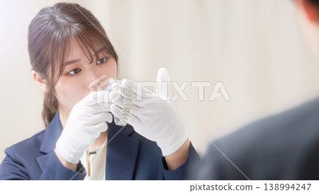 A female appraiser examines the watch with a magnifying glass during the appraisal process. 138994247