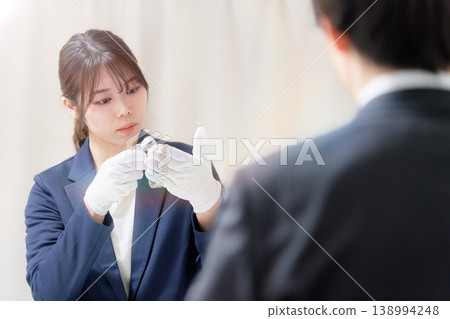 A female appraiser examines the watch with a magnifying glass during the appraisal process. A female appraiser examines the watch with a magnifying glass during the appraisal process. 138994248