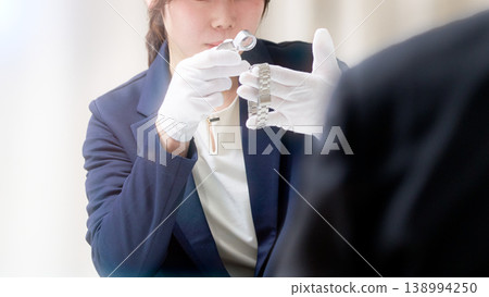 一位女鑑定師正在用放大鏡檢查一隻手錶。 一位女鑑定師正在用放大鏡檢查一隻手錶。 138994250