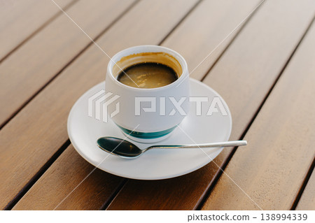 Cup of black coffee on a wooden table in a cafe. Cup of black coffee on a wooden table in a cafe. 138994339
