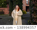 Smiling woman standing outdoors in autumn courtyard 138994357