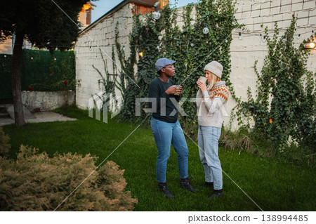 Diverse women friends enjoying conversation with coffee in backyard 138994485