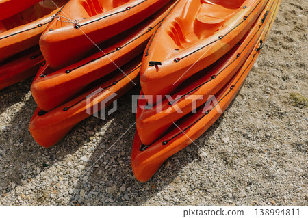 Colorful orange kayaks on a sandy beach in sunny day. Colorful orange kayaks on a sandy beach in sunny day. 138994811